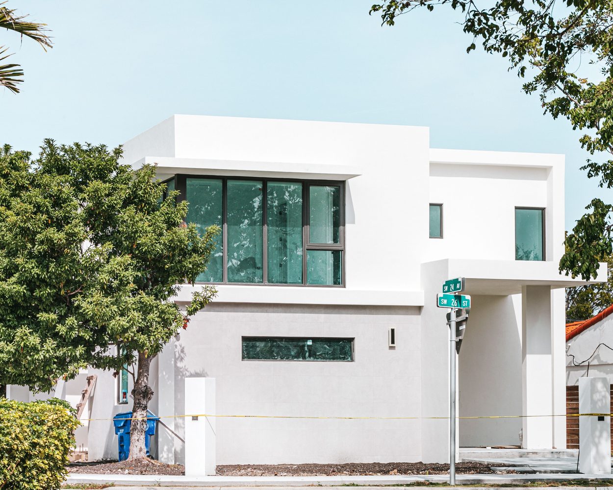 Fachada branca reformada com esquadrias escuras e brises horizontais